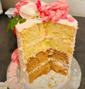 A sliced four-layer cake topped with pink sugar flowers